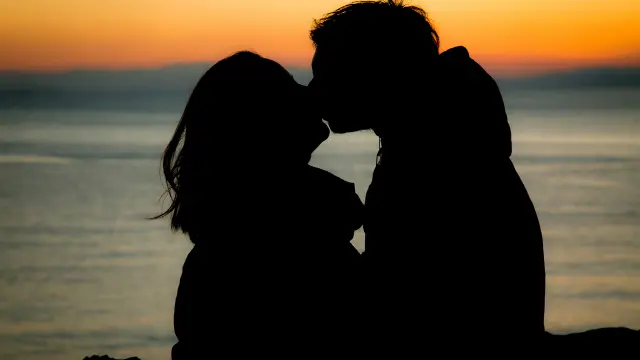 Deux silhouettes s'embrassent devant un coucher de soleil sur la plage