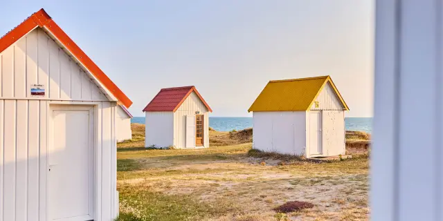 Three beach huts with roofs of different colors