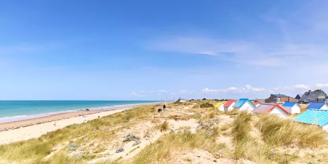 Plage de sable avec des cabines colorées et la mer en arrière plan à Gouville sur Mer