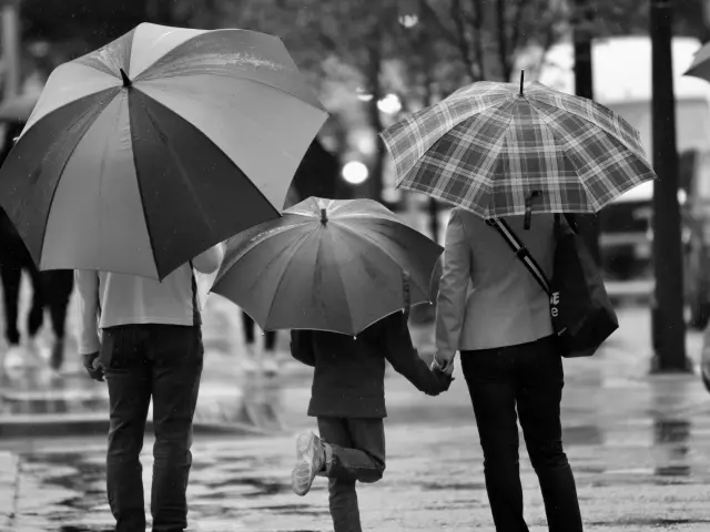Eine Familie geht im Regen mit Regenschirmen