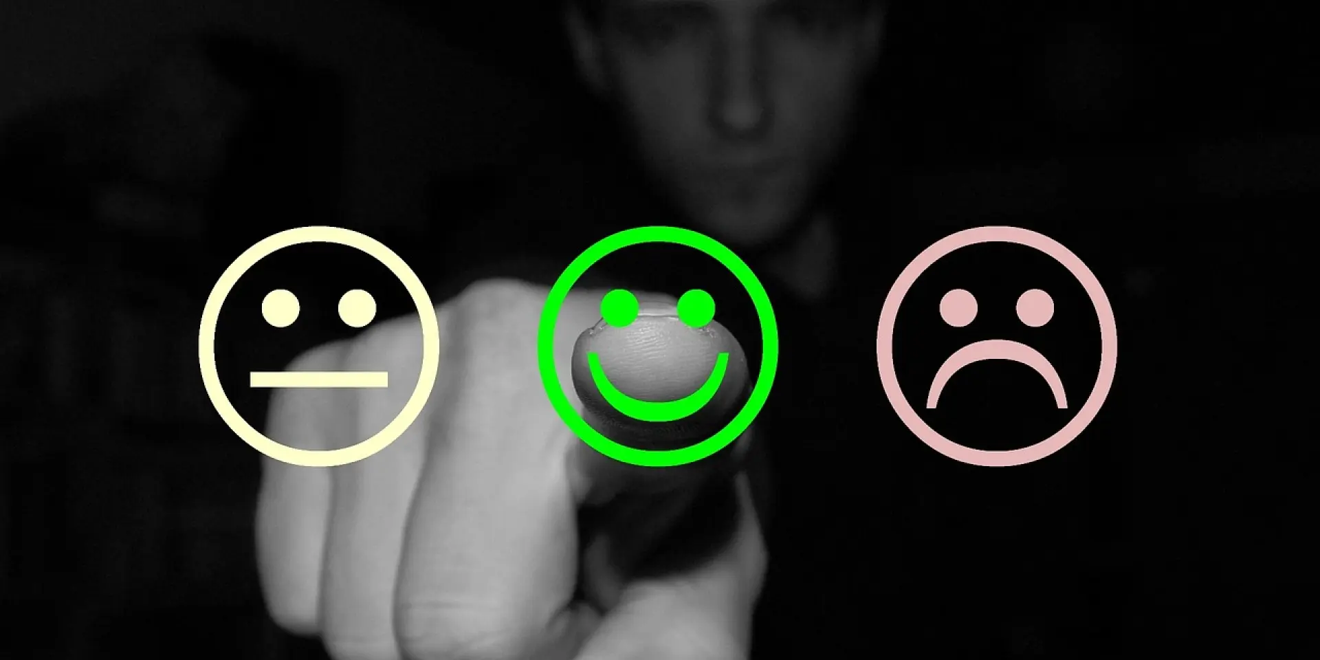 Main pointant vers un emoji souriant entouré de deux autres emoticônes
