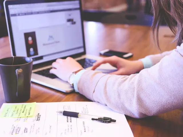 Personne travaillant sur un ordinateur portable avec une tasse de café à côté