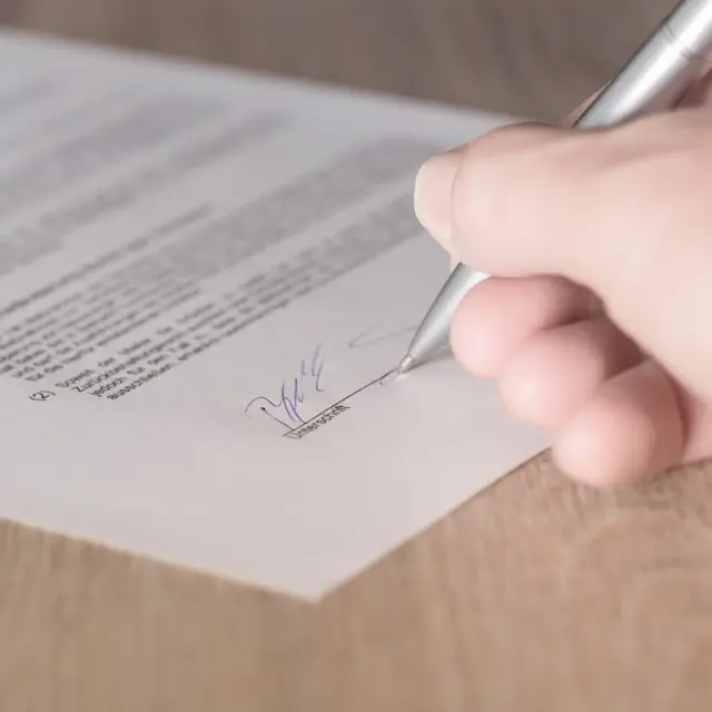 Une main signe un document avec un stylo