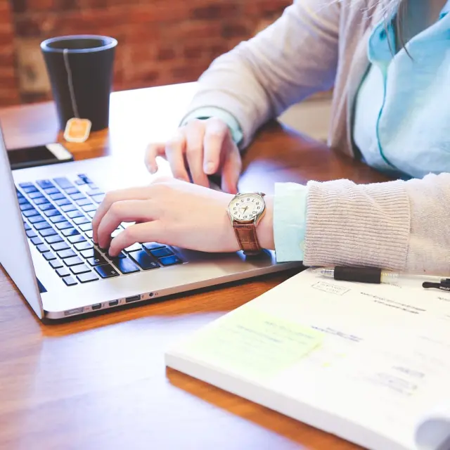Personne travaillant sur un ordinateur portable avec des documents à côté