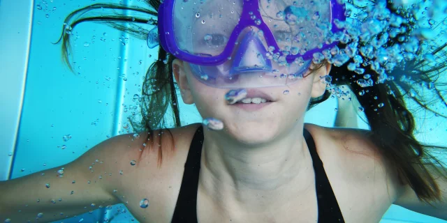 Jeune fille sous l'eau avec un masque de plongée bleu