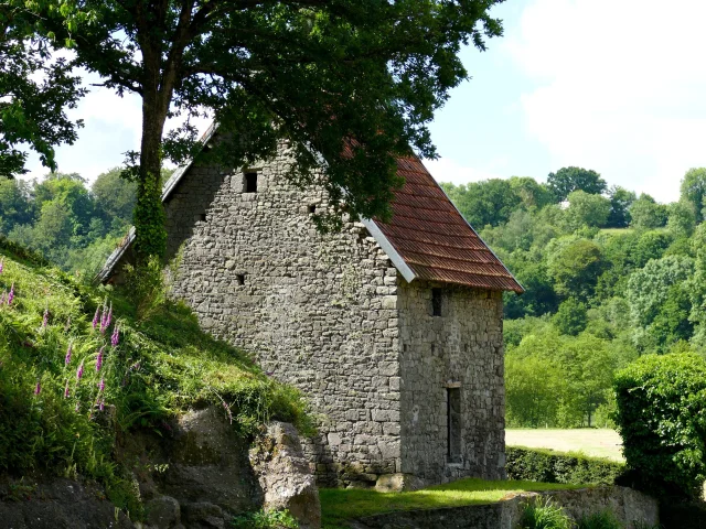 Stone house with a red tiled roof surrounded by trees and greenery