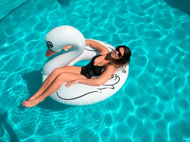 Une femme en maillot de bain noir sur un canard gonflable blanc dans une piscine