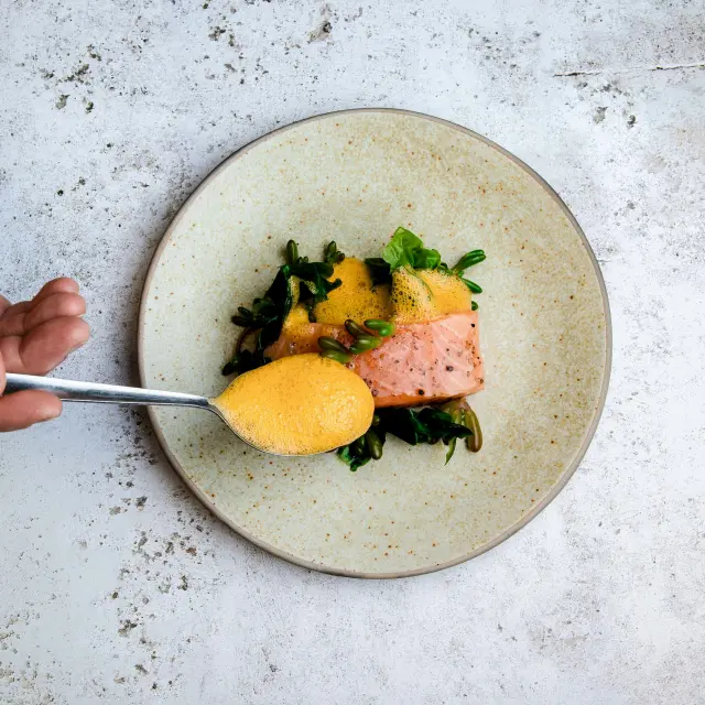 Assiette avec un plat composé de poisson, de purée de patate douce et de légumes verts