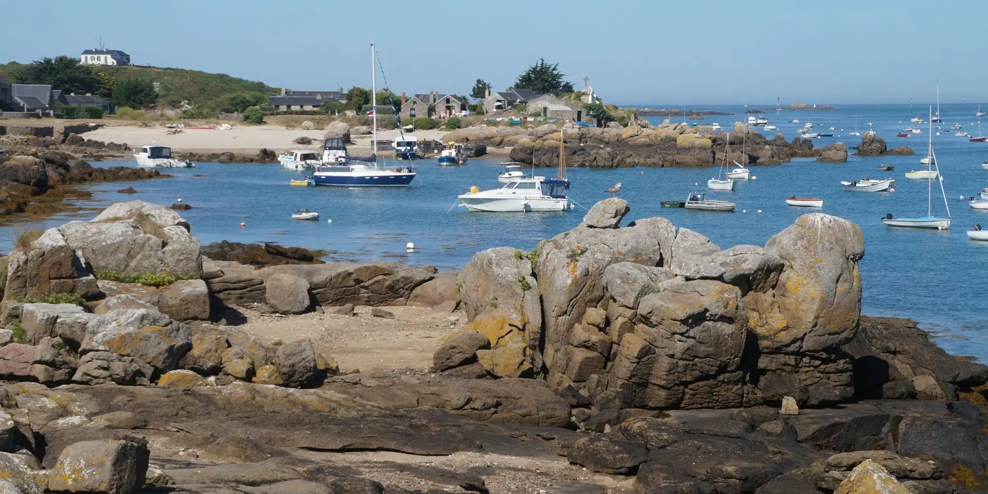 Boats anchored in a fishing harbor with rocks in the foreground