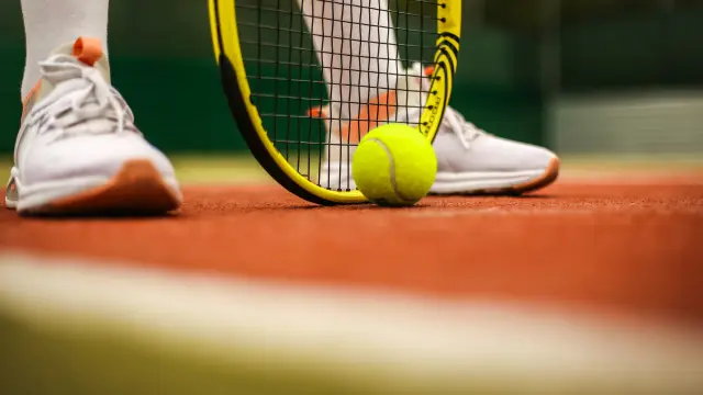 Feet of a tennis player with racket and ball