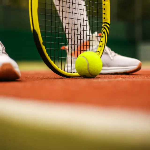 Füße eines Tennisspielers mit Schläger und Ball