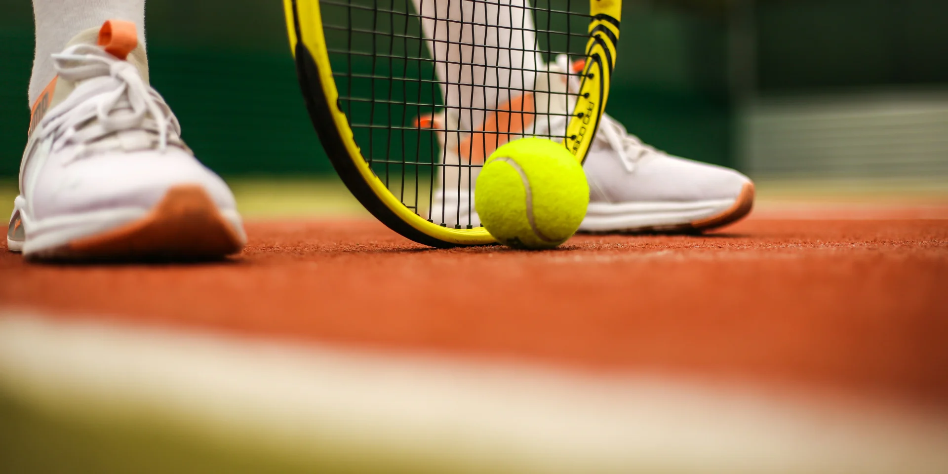 Feet of a tennis player with racket and ball