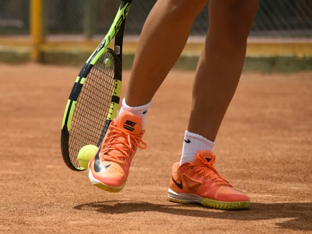 Tennis player hitting a ball with a racket on a clay court