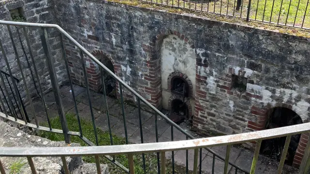 Ansicht eines verfallenen alten Brotbackofens umgeben von einem Metallzaun