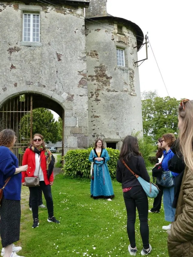 Un groupe de personnes écoutant une guide en costume traditionnel devant un bâtiment ancien au château de Chanteloup
