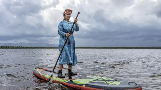 Personne en tenue traditionnelle sur une planche de paddle