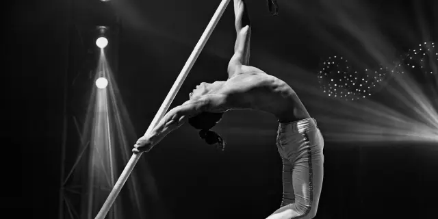 Un acrobate effectuant une figure sur un tissu aérien sous les projecteurs