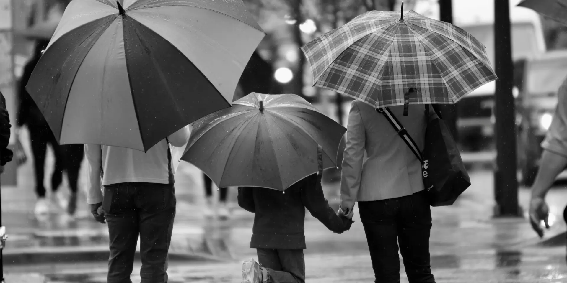 Trois personnes marchant sous la pluie avec des parapluies