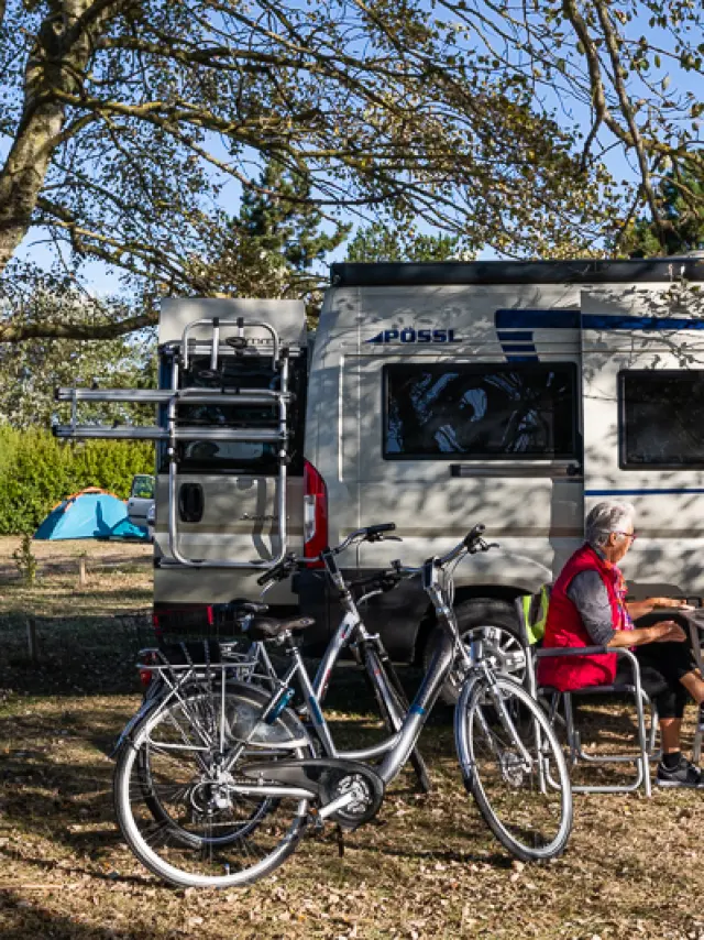 Deux personnes assises devant un camping-car avec des vélos