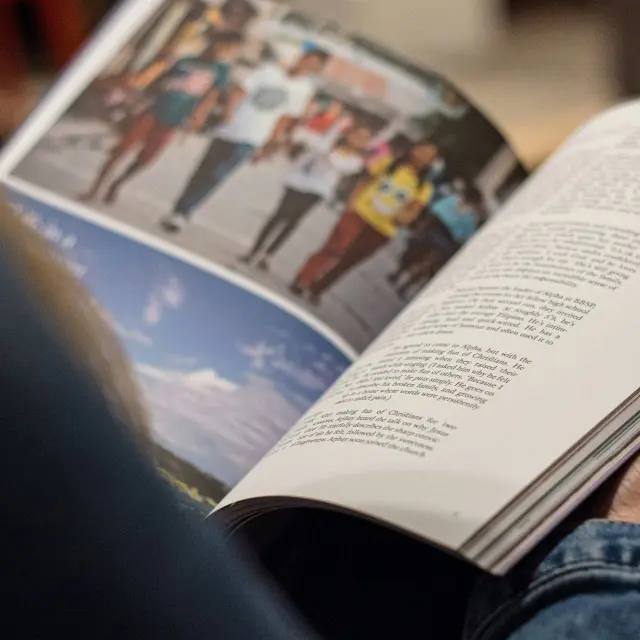 Personne lisant un livre avec des images de personnes et de paysages : bulletin municipal