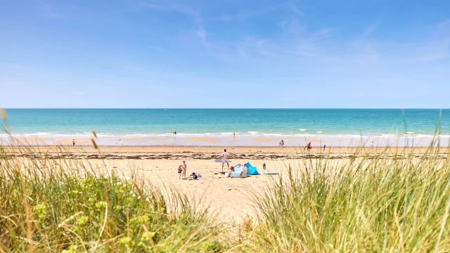 Personnes profitant d'une journée ensoleillée sur une plage de sable à Gouville Sur Mer