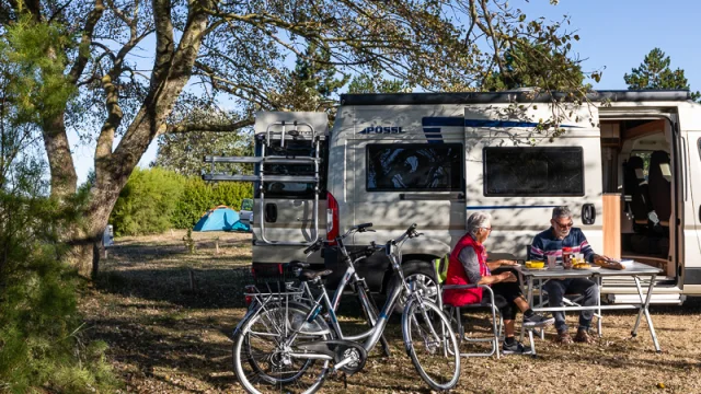 Deux personnes assises devant un camping-car avec des vélos