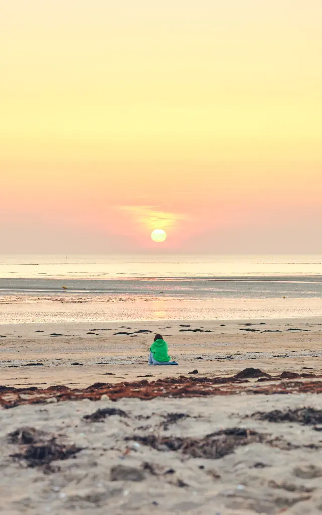 A person in silhouette on a beach at sunset