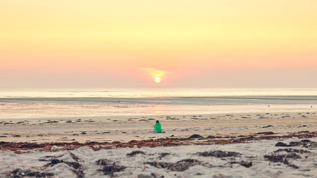 Une personne en silhouette sur une plage de Lingreville au coucher du soleil