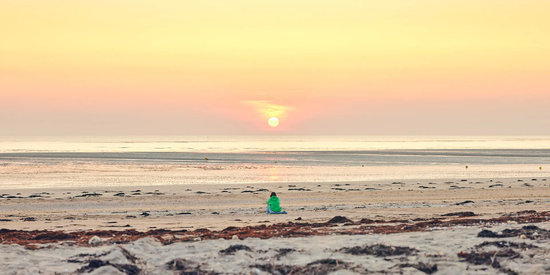 Une personne en silhouette sur une plage de Lingreville au coucher du soleil