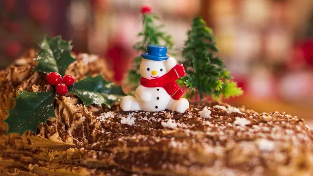 Christmas Yule log decorated with a snowman and holly branches