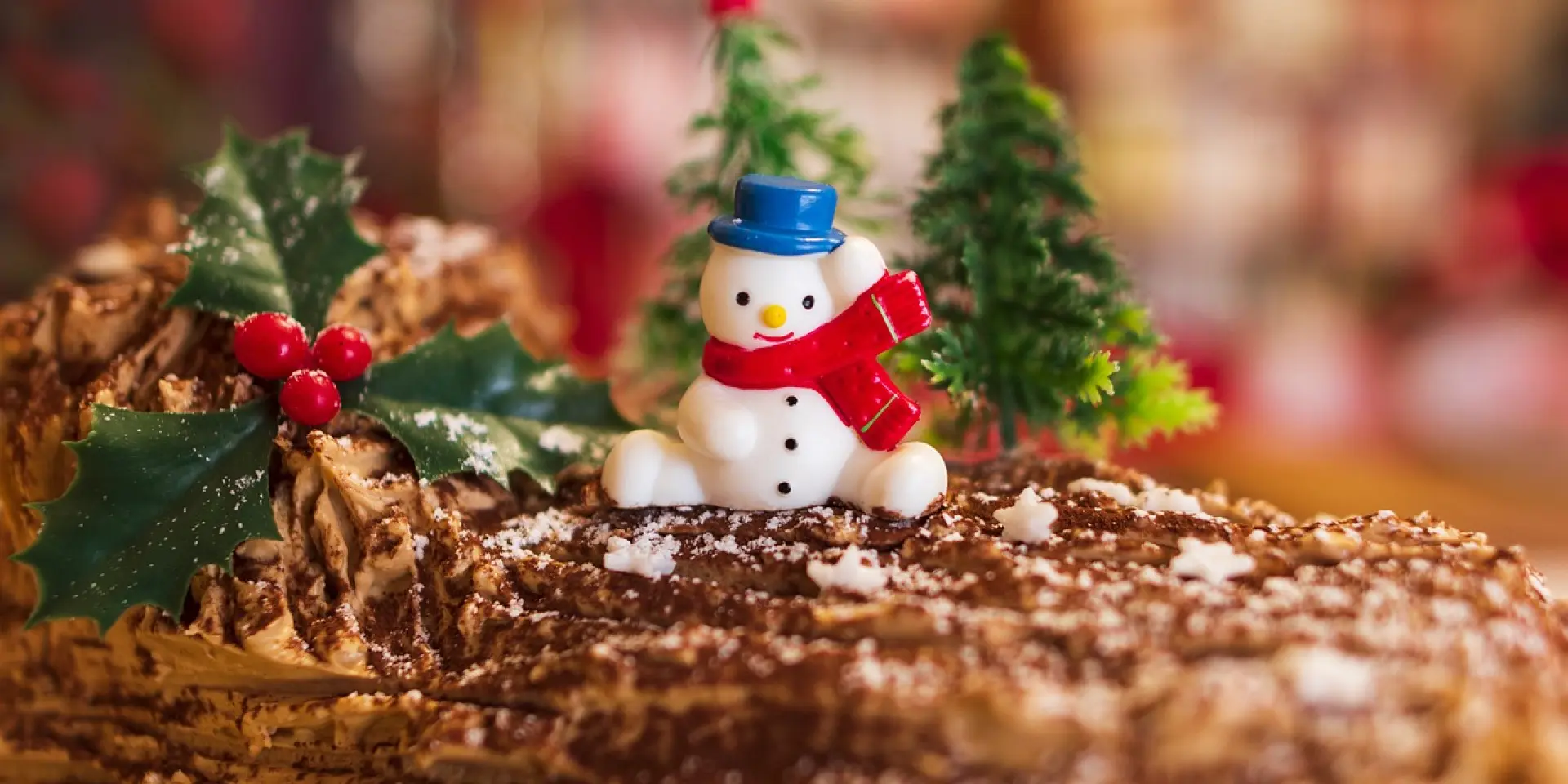 Christmas Yule log decorated with a snowman and holly branches