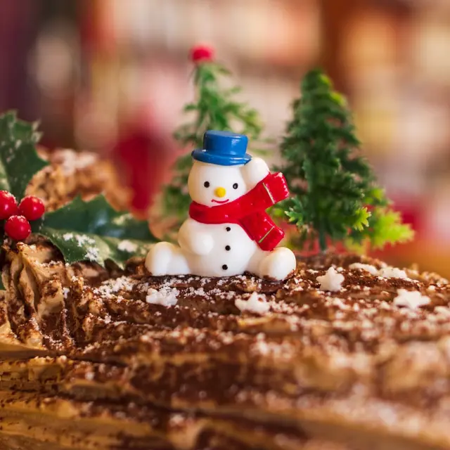 Christmas Yule log decorated with a snowman and holly branches