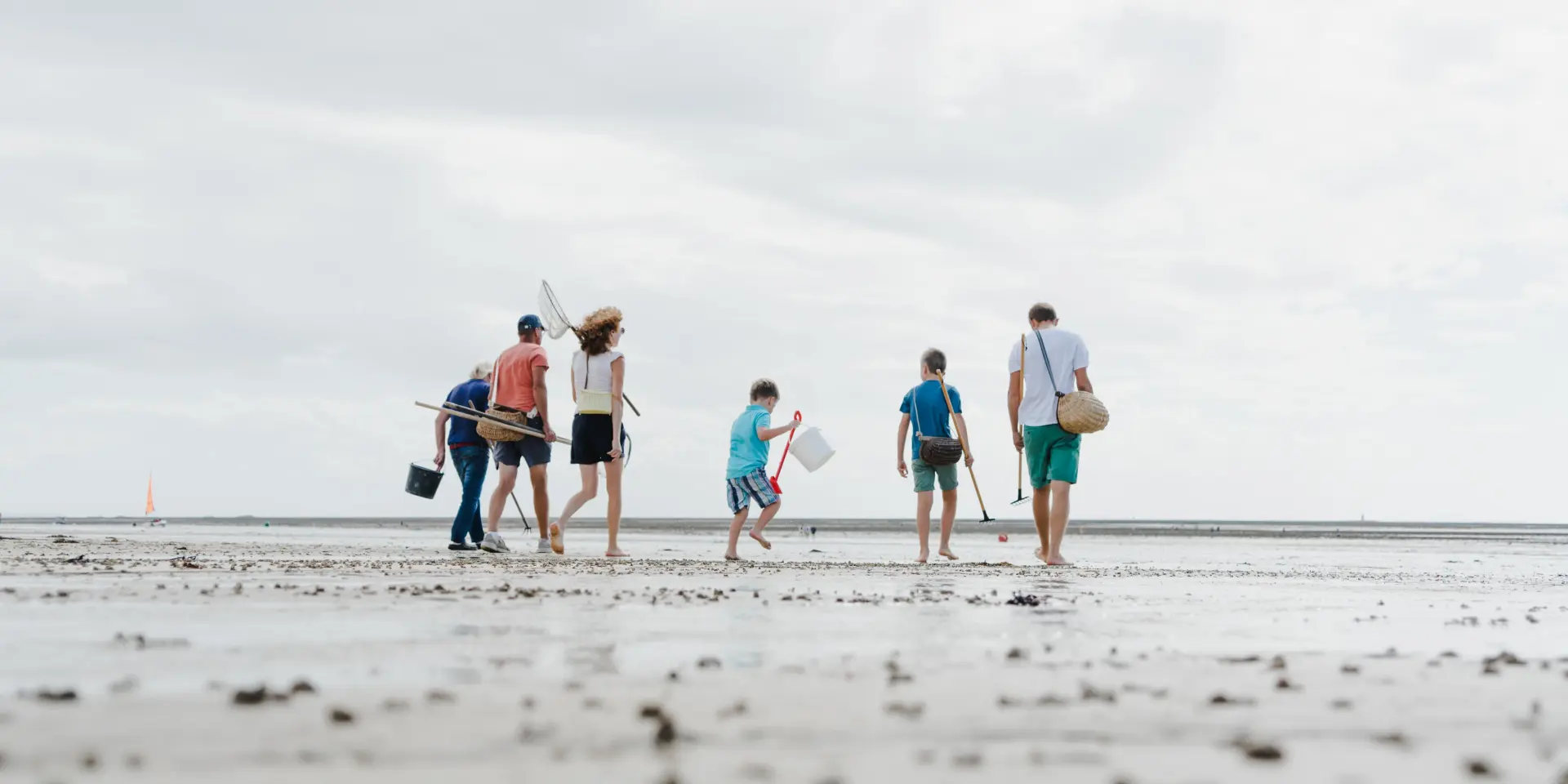 Une famille marche sur une plage à la recherche de coquillages