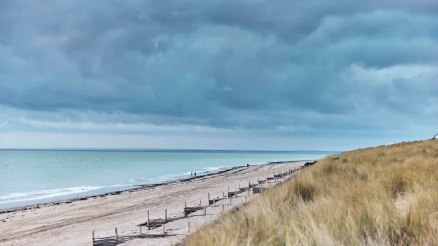 Plage de sable à Gouville-sur-Mer avec des nuages sombres au-dessus
