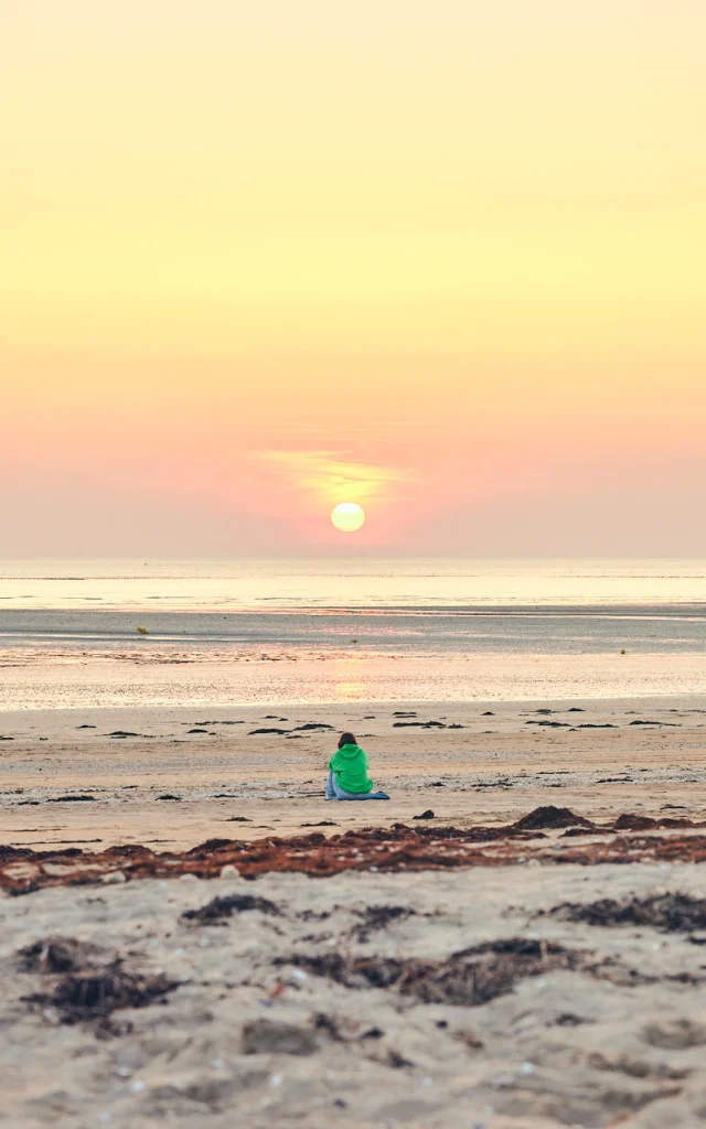 Une personne en silhouette sur une plage de Lingreville au coucher du soleil