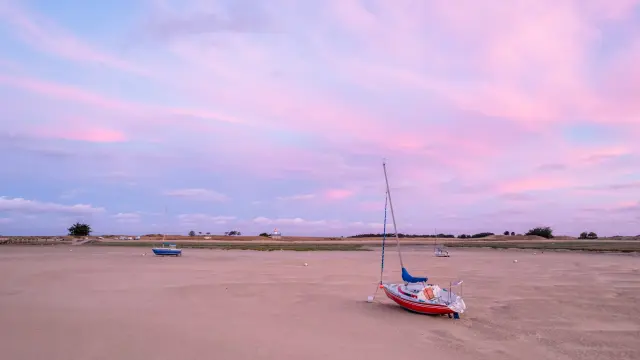 Eine Segeljacht auf einem einsamen Strand bei Sonnenuntergang gestrandet