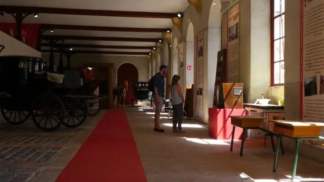 Menschen besuchen ein Museum mit Ausstellungen und einem alten Wagen