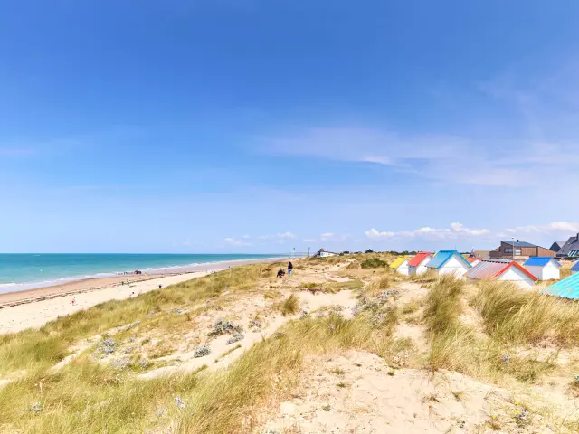 Sandstrand mit bunten Strandhäuschen und dem Ozean im Hintergrund