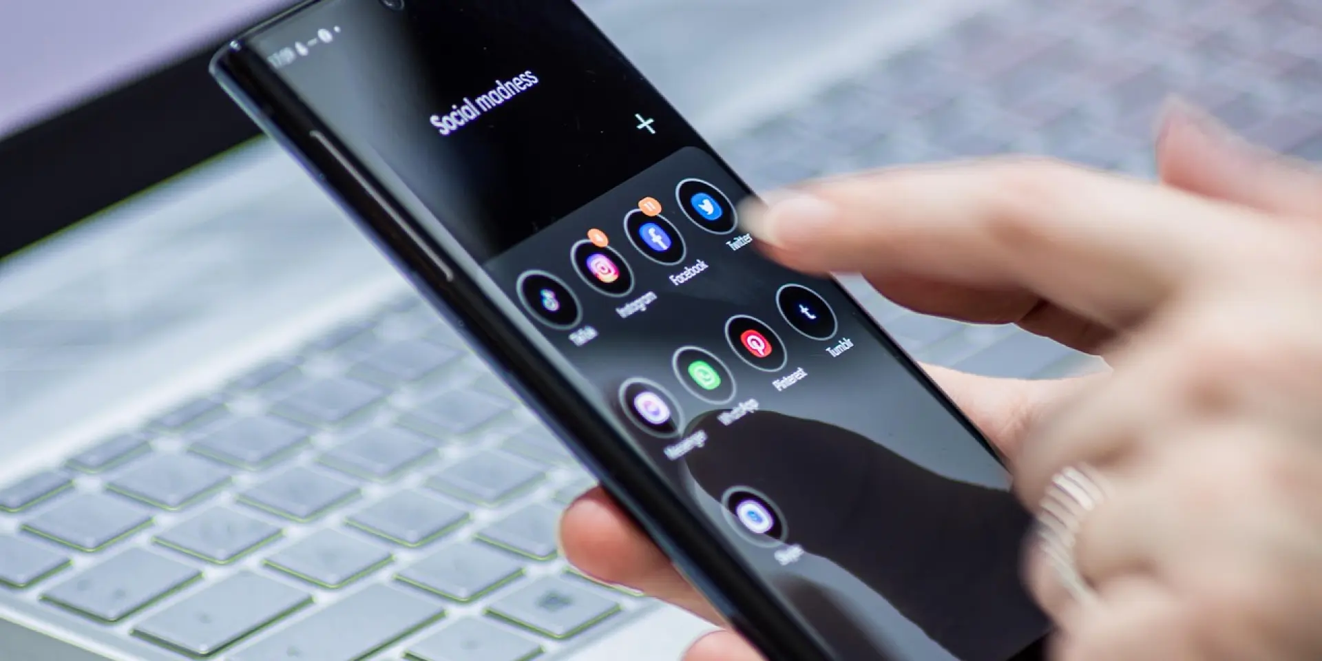 Main tenant un smartphone affichant des icônes d'applications sociales