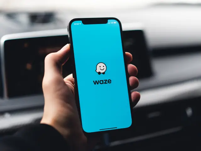 Main tenant un smartphone affichant l'application Waze