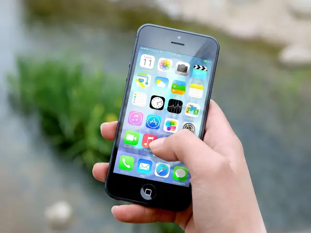 Main tenant un smartphone affichant des icônes d'applications