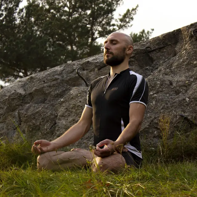 Homme assis en position de méditation devant un rocher
