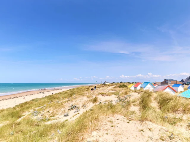Sandy beach with colorful beach huts and the ocean in the background