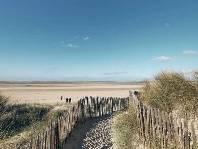 Wooden path leading to a deserted beach under a blue sky