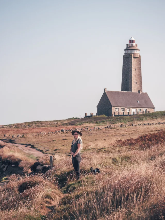 A hiker in hiking gear in front of a lighthouse