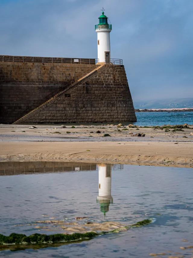Lighthouse on a pier with its reflection in the water