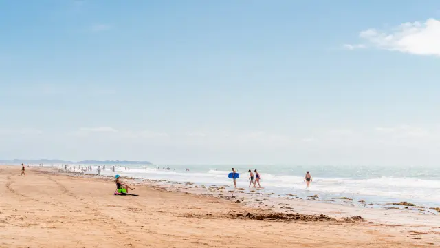 Personnes se promenant et jouant sur une plage de sable à Lingreville
