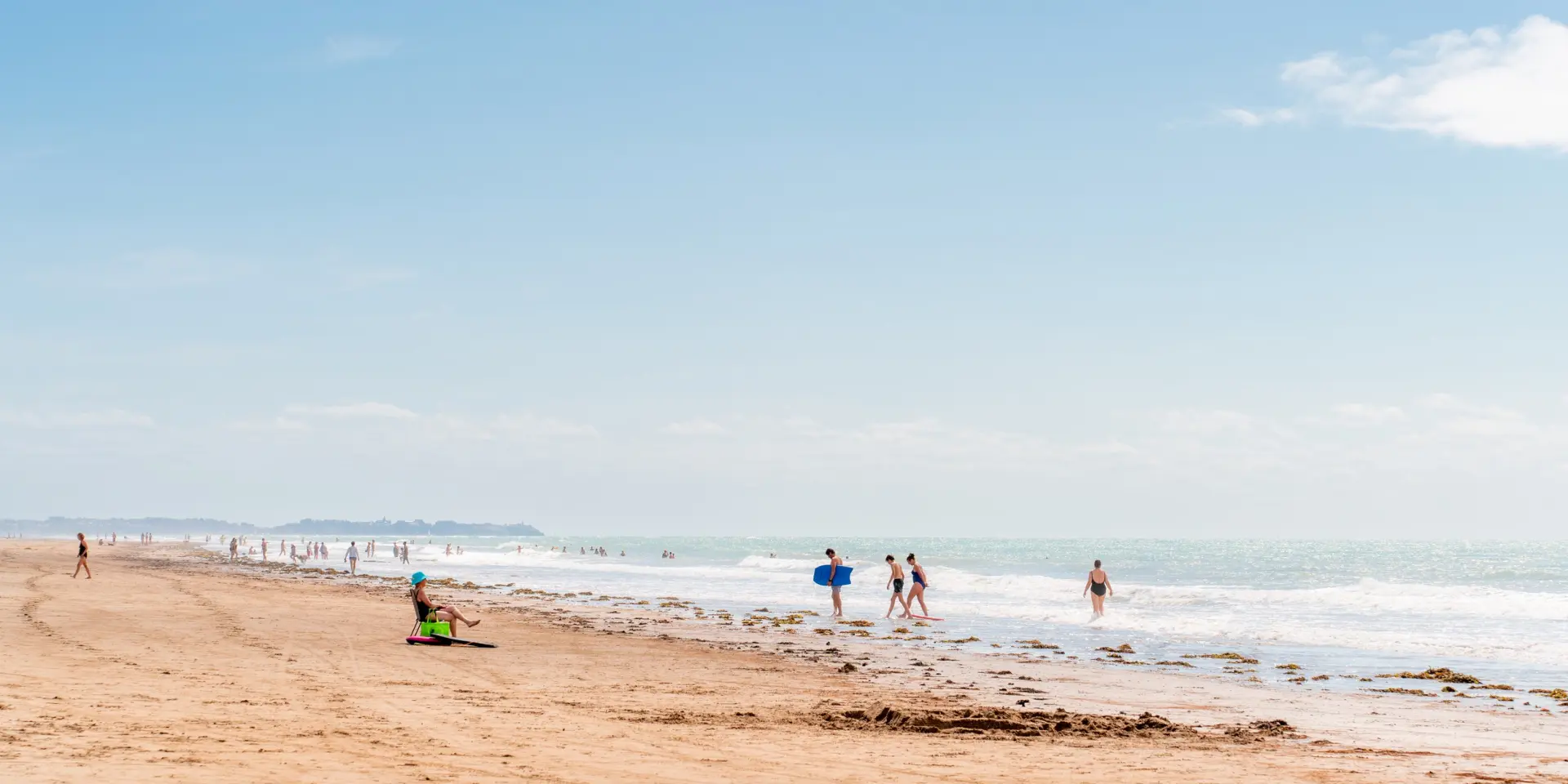 Personnes se promenant et jouant sur une plage de sable à Lingreville