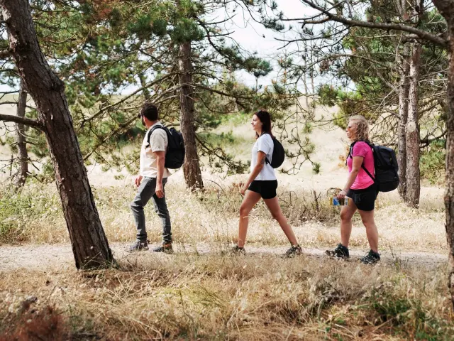 Trois personnes marchant sur un sentier en bord de mer