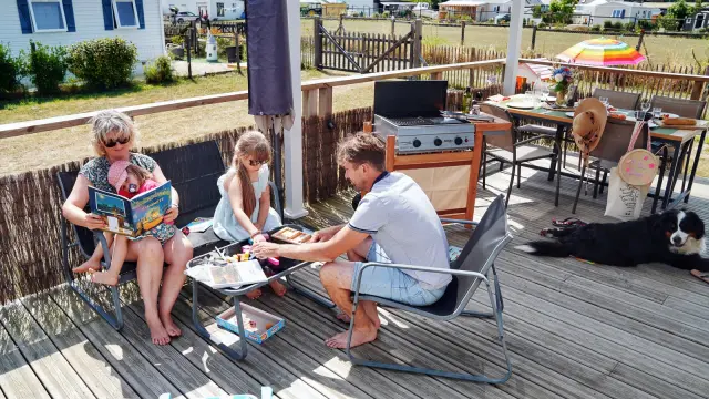 A family on a camping vacation, reading and eating on a wooden terrace